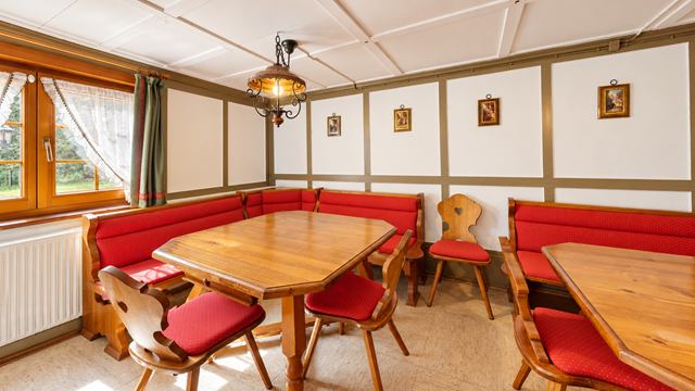 Maisachstube mit roten Eckbänken und Tischen